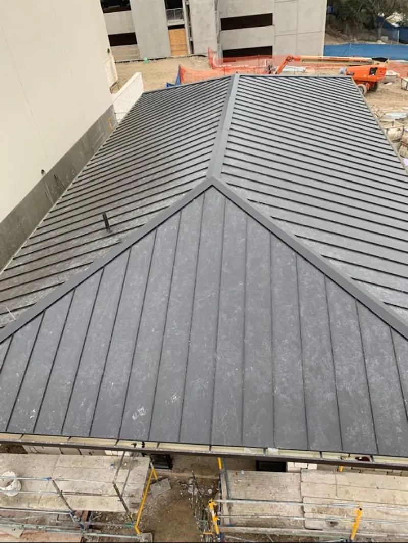 Commercial metal roof construction with crane equipment in Gates